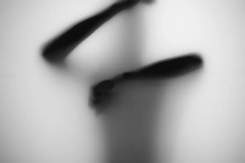 Two forearms angled across frosted glass as dark, near-abstract shapes.